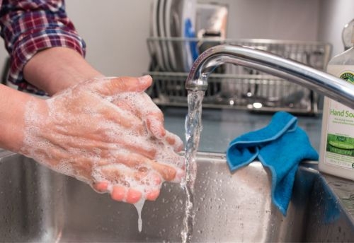 Persona se lava las manos con agua y jabón para quitarse el polvo.
