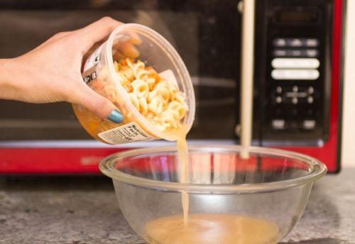 Mujer transfiere sopa de un contenedor de plástico a uno de vidrio para calentarla de forma segura en el microondas.