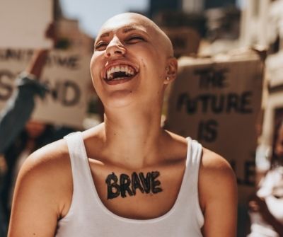 Woman at a protest with BRAVE written on her chest. 
